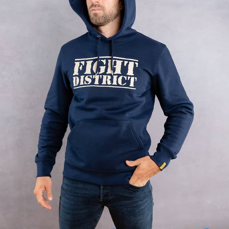 Photo de face d'un homme portant un hoodie bleu foncé au logo blanc de la collection The Original