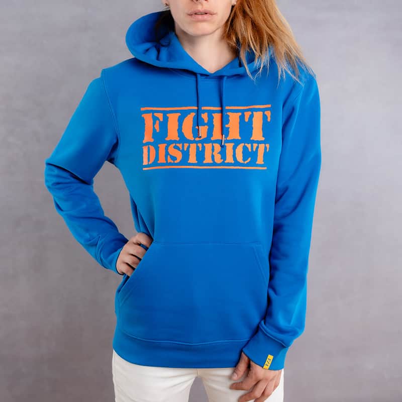 Photo de face d'une femme portant un hoodie bleu au logo orange de la collection The Original