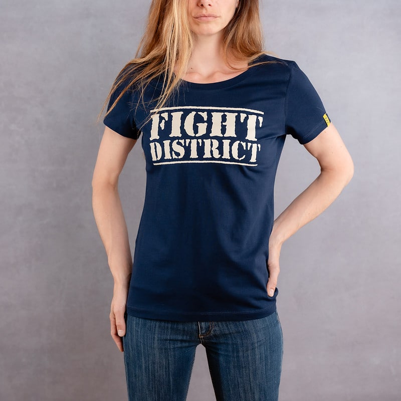 Photo de face d'une femme portant un T-shirt bleu foncé au logo blanc de la collection The Original