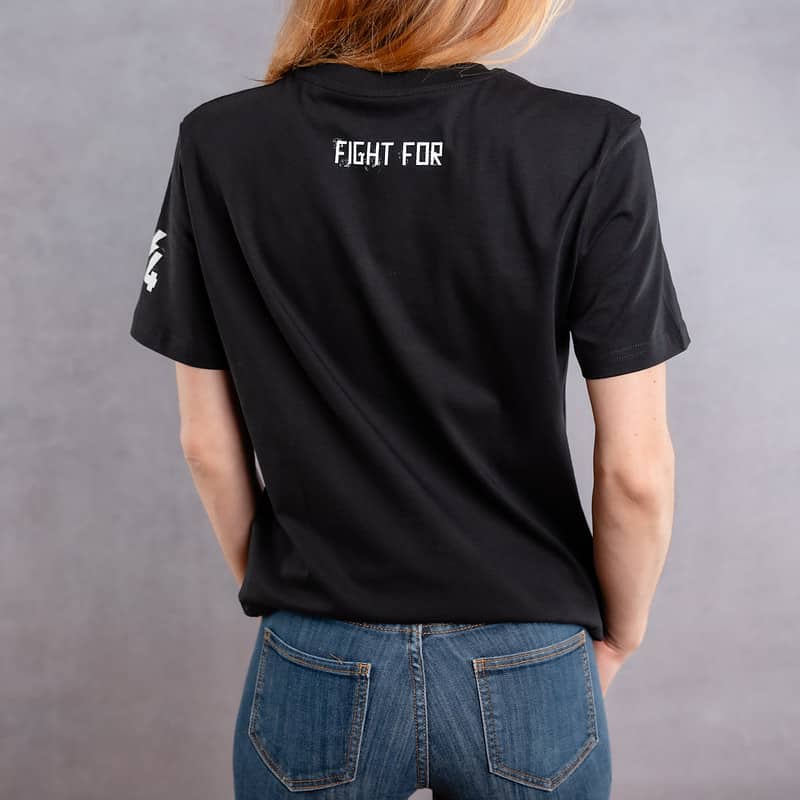 Back photo of a woman wearing a black T-shirt with a white logo from the Cabal Skull collection.
