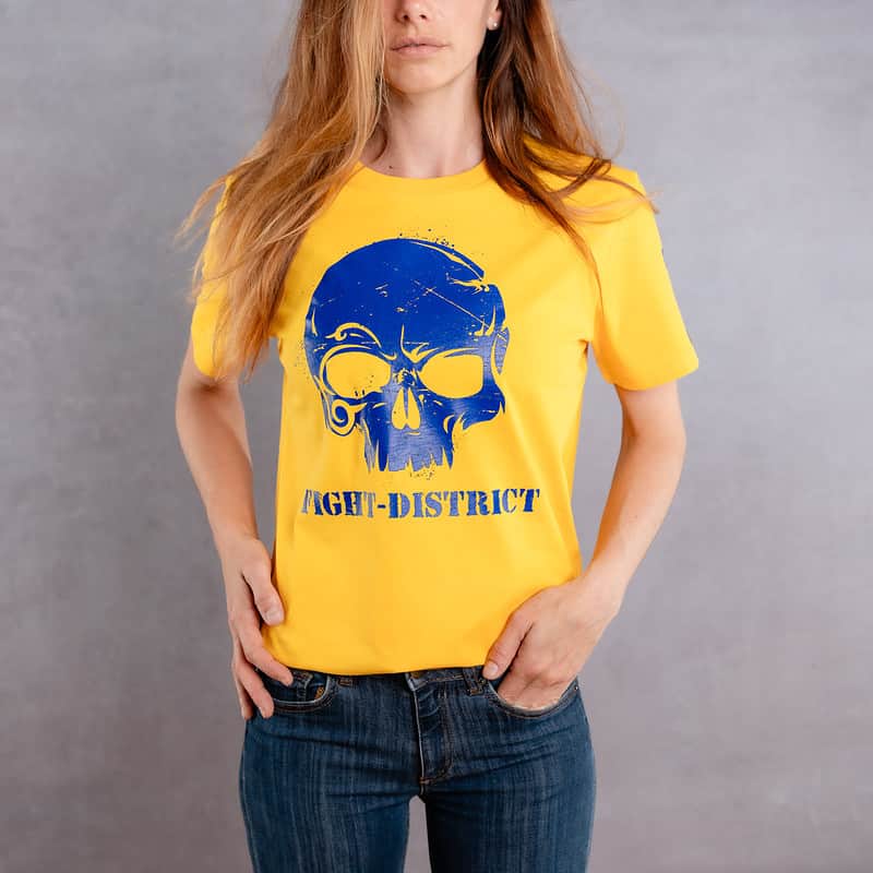 Image de face d'une femme portant un T-Shirt jaune au logo bleu de la collection Cabal Skull