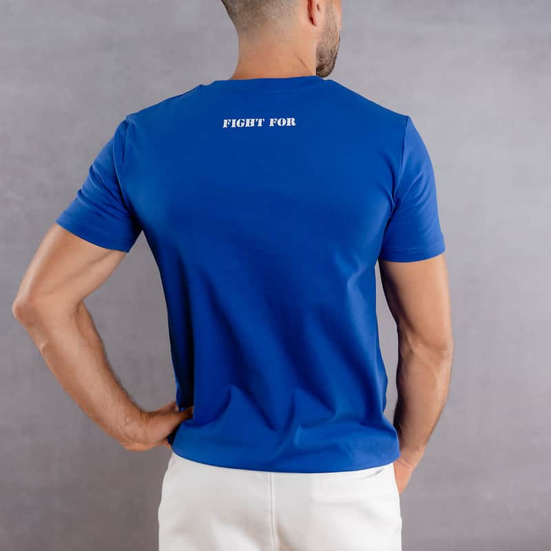 Image de dos d'un homme portant un T-Shirt bleu roi au logo blanc de la collection The Original