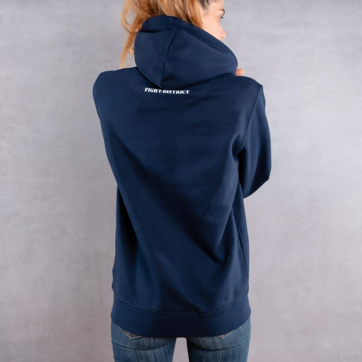 Image de dos d'une femme prenant la pose et portant un hoodie bleu foncé au logo blanc de la collection Laurier