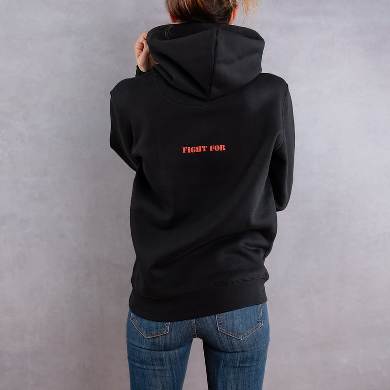 Image de dos d'une femme portant un hoodie noir au logo rouge de la collection The Original