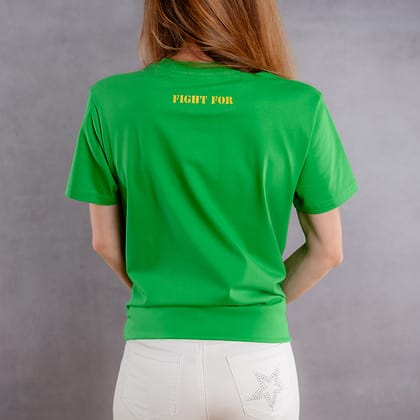 Photo de dos d'une femme portant un T-shirt vert au logo jaune de la collection The Original