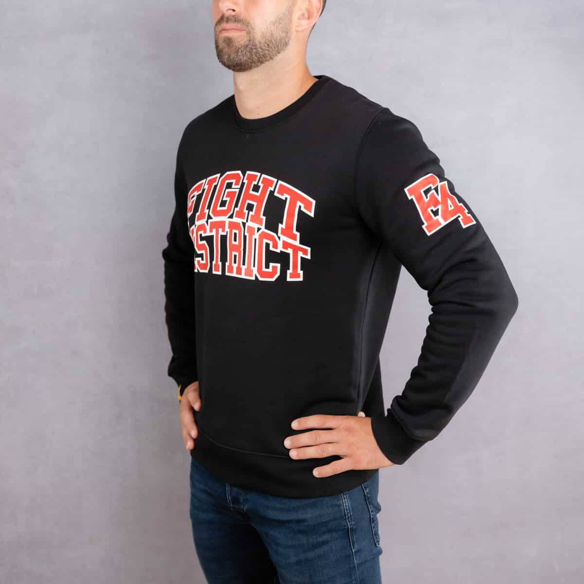 Image de côté d'un homme portant un pull noir au logo rouge de la collection College