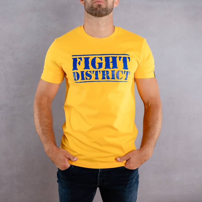 Image de face d'un homme portant un T-Shirt jaune au logo bleu de la collection The Original