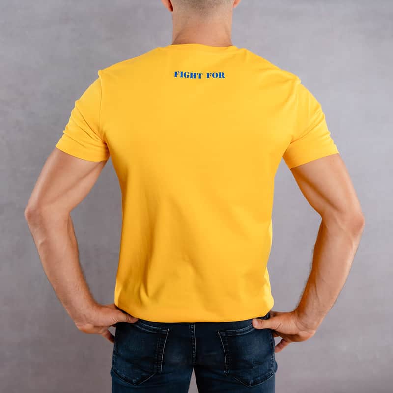 Image de dos d'un homme portant un T-Shirt jaune au logo bleu de la collection The Original