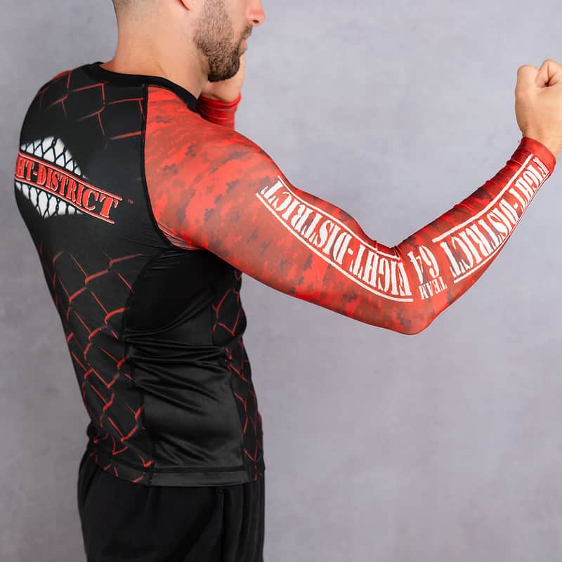 Rashguard avec des camouflages rouge et noir sur les manches porté par un homme de profil se mettant en garde avec le logo de la salle de sport fight-district