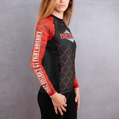 Rashguard de profil avec du camouflage rouge sur les bras et le logo de la salle de sport Fight-District porté par une femme