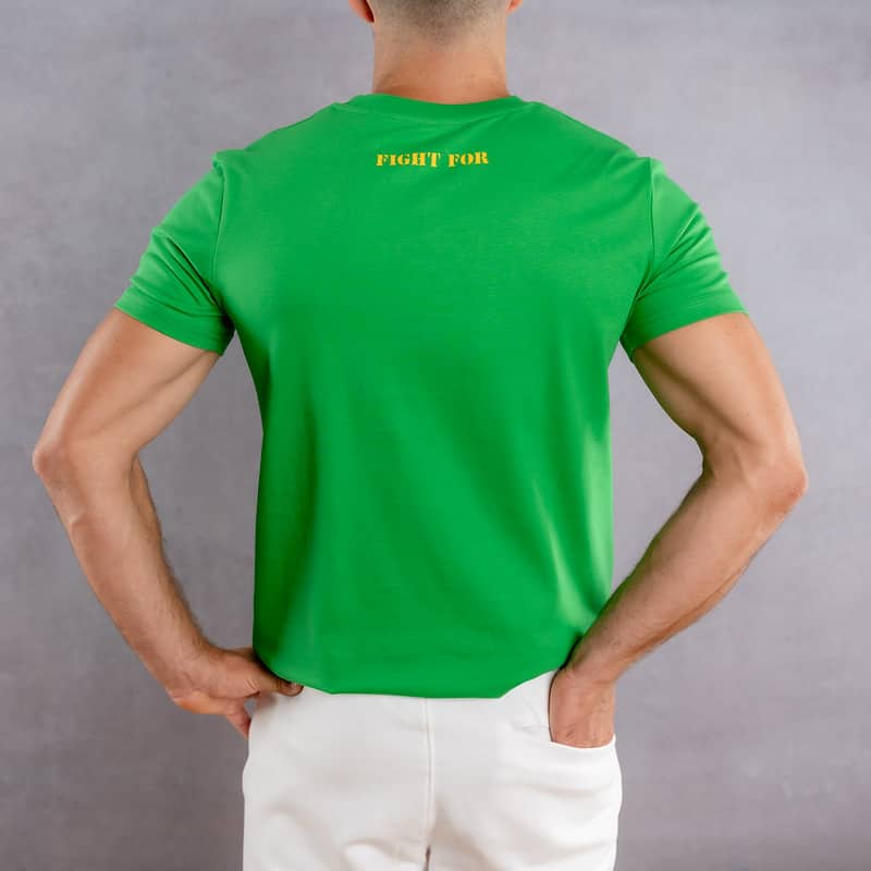 Image de dos d'un homme portant un T-Shirt vert au logo jaune de la collection The Original