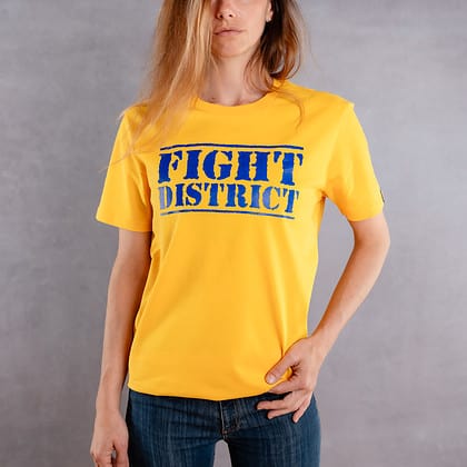 Photo de face d'une femme portant un T-shirt jaune au logo bleu de la collection The Original