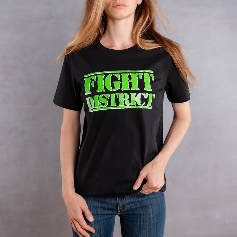 Photo de face d'une femme portant un T-shirt noir au logo vert de la collection The Original
