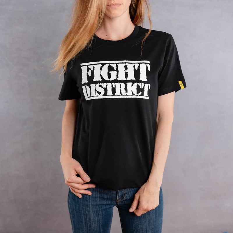 Front view of a woman wearing a black T-shirt with a white logo from The Original collection.