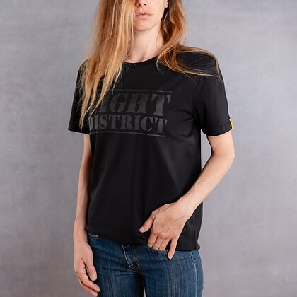 Photo de face d'une femme portant un T-shirt noir au logo noir de la collection The Original