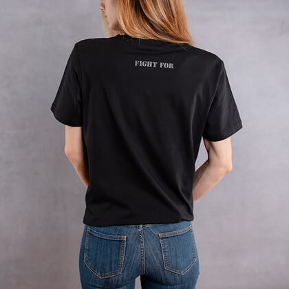 Photo de dos d'une femme portant un T-shirt noir au logo noir de la collection The Original