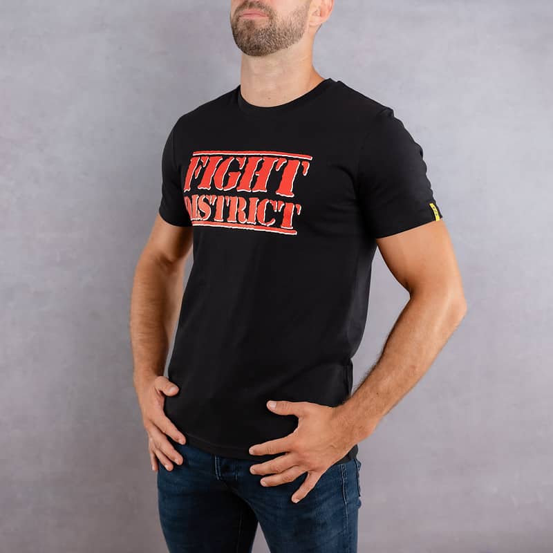 Image de côté d'un homme portant un T-Shirt noir au logo rouge de la collection The Original